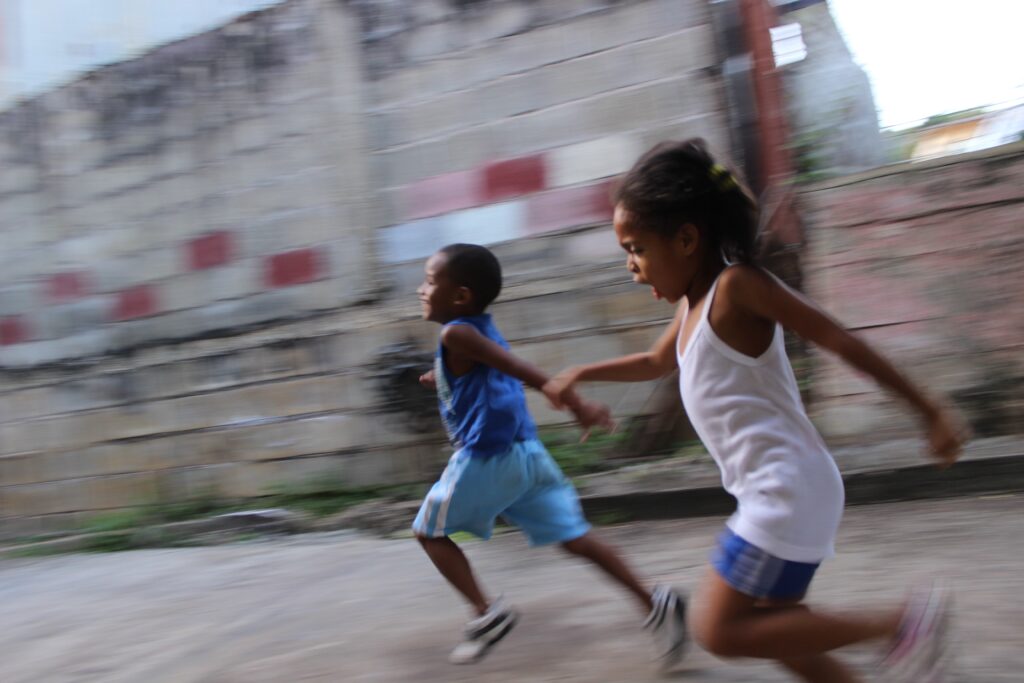 two children running together, holding hands.