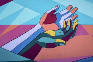 two hands together, painted in various colors.