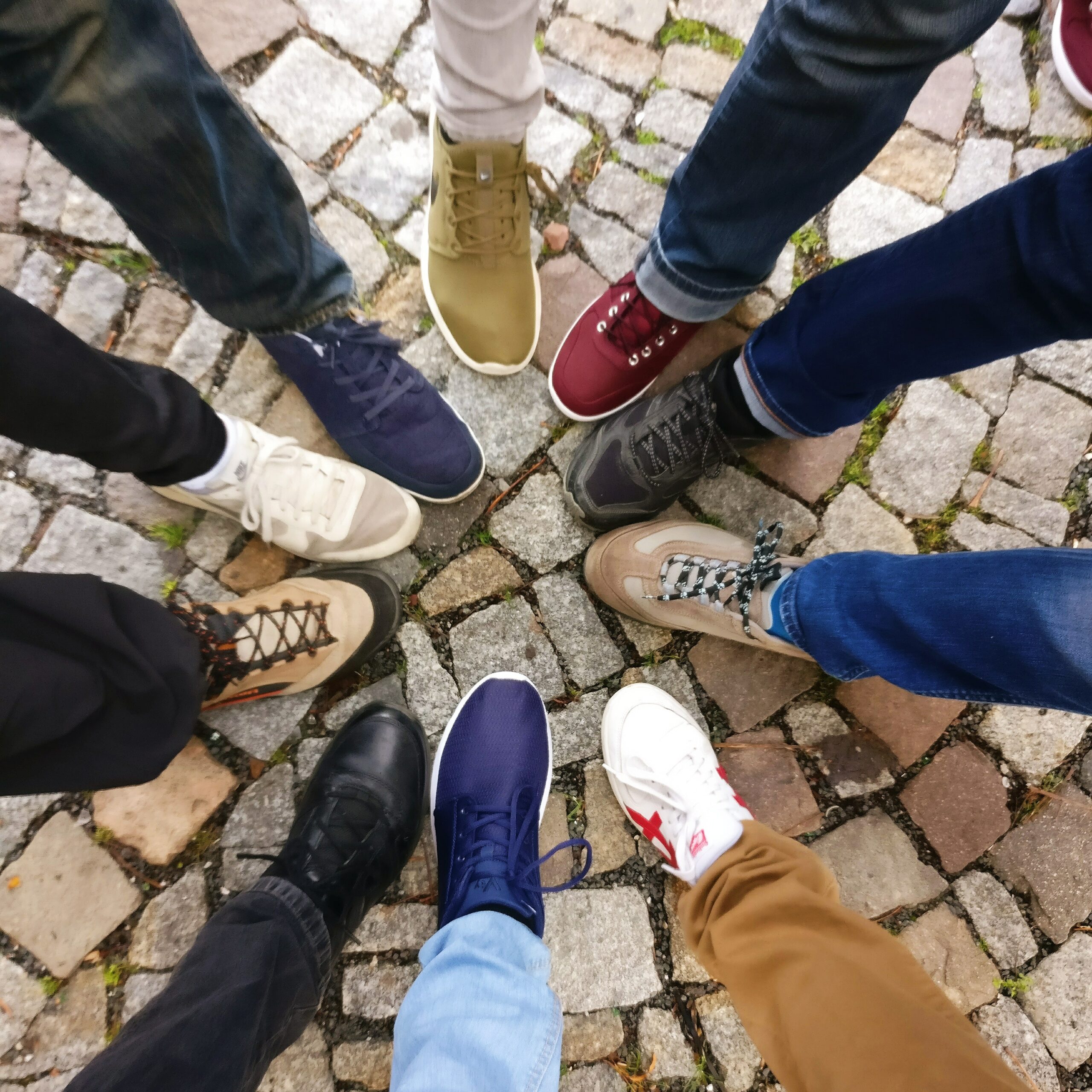 Image shows ten feet stepping into a circle on a cobblestone path, indicating community or team spirit.