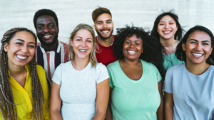 Seven adults in colourful tee shirts are smiling.